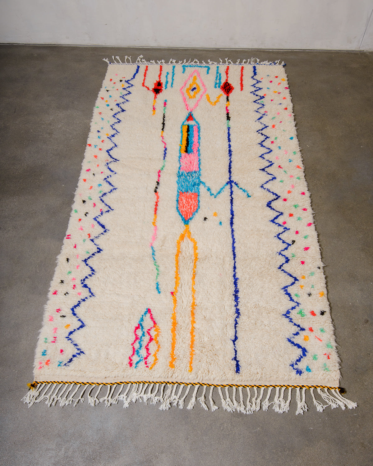 Berberlin Azilal rug made of fluffy wool and colourful cotton, laying flat on a concrete floor.